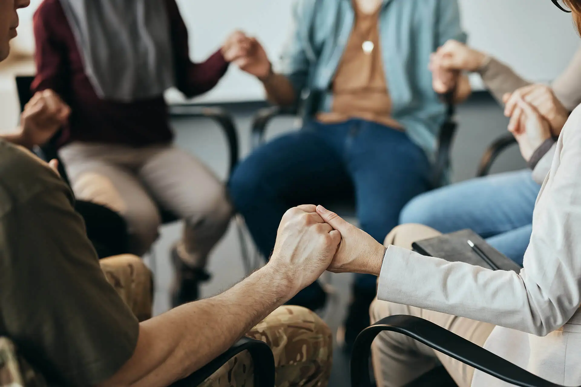 close up of group therapy attenders holding hands DGUQWYG 1